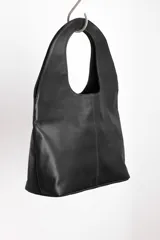 Bolso tote negro de cuero con manija circular rígida.