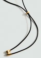 Collar con cordón de cuero negro y adorno metálico dorado con diseño de hojas.