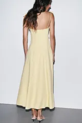 Vestido midi amarillo claro, con escote corazón con volantes y tirantes finos ajustables con lazo. Falda acampanada con forro interior.