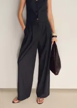 Pantalón largo de vestir a rayas verticales, con tiro medio, corte recto y cierre frontal con cremallera y botón. Confeccionado en tejido de mezcla de algodón y lino con forro interior de algodón.