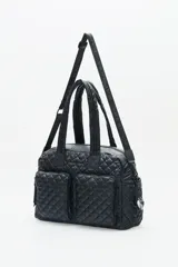 Bolso marrón con diseño matelassé, doble asa corta, correa larga desmontable y dos bolsillos frontales. Incluye llavero de corazón y dijes desmontables.