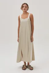 Vestido largo color beige de lino metalizado, con tirantes anchos a contratono y corte recto con abertura lateral.