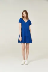 Vestido corto lila con cuello en V y mangas cortas. Tiene corte holgado y dos volados en la falda.