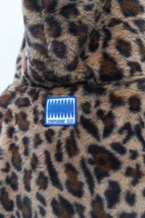 Chaqueta con capucha de tela tipo peluche con estampado animal print de leopardo, cierre frontal con cremallera y cordón ajustable en la capucha.