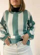 Sweater tejido a rayas horizontales anchas en color celeste y blanco, con sutil brillo. Diseño amplio y cómodo.