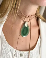 Collar con colgante de piedra natural en tono verde, suspendido de un cordón de cuero.