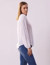 Blusa blanca de manga larga con cuello redondo y detalle de broderie en el canesú.