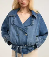 Campera corta tipo trench coat confeccionada en tejido denim de algodón. Presenta cuello con solapa, escote en V, manga larga, cierre frontal con botones y lazo en la cintura.