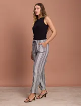 Pantalón largo de lino y rayón a rayas verticales grises y blancas. Tiene pretina elastizada con lazo de ajuste, bolsillos delanteros y traseros.