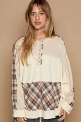 Blusa oversize estilo patchwork, con combinación de paneles lisos y a cuadros. Mangas largas holgadas con puños y tapeta con botones metálicos.