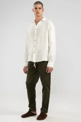 Camisa de manga larga color blanco hueso, confeccionada en lino, con cuello clásico y cierre frontal con botones de coco.