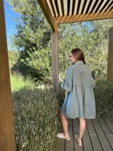 Vestido camisero azul de lino italiano, con cuello camisero, botones frontales, mangas 3/4 con doble volado y bolsillos laterales.