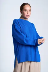 Sweater color beige de tejido de punto acanalado, con cuello redondo y mangas largas. Tiene corte holgado y aberturas laterales en el ruedo.