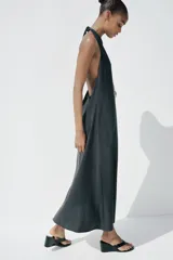 Vestido midi negro de tejido fluido, con cuello halter que se ata al cuello, escote en V y espalda descubierta.