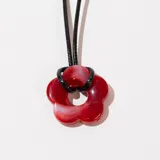 Collar con colgante de flor roja y cordón negro con cadena de alargue plateada.