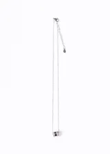 Collar plateado con cadena fina y dije cilíndrico negro con dos bandas de circonias blancas.