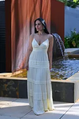 Vestido largo color amarillo manteca con breteles finos, escote en V y falda con volados.