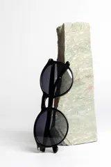 Lentes de sol unisex con montura redonda negra y lentes degradadas de gris a transparente.