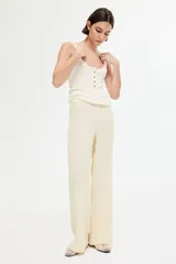 Pantalón de corte holgado color crema, confeccionado en tejido de punto con textura. Modelo de tiro alto con cintura elástica y piernas rectas.