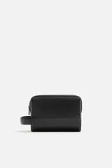 Neceser negro rectangular con cierre de cremallera y asa lateral. El interior tiene un bolsillo con cierre mediante cremallera.