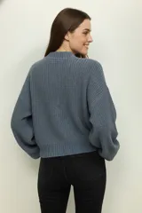 Sweater de tejido de punto grueso color blanco roto, con cuello redondo y mangas largas abullonadas. El calce es holgado y corto (cropped).