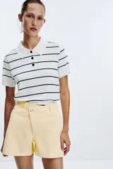 Shorts de jean celeste con tiro alto, cinco bolsillos y cierre frontal cruzado con cremallera y botones.