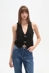 Chaleco blanco de algodón con escote en V profundo y cierre frontal ajustable mediante dos hebillas metálicas.