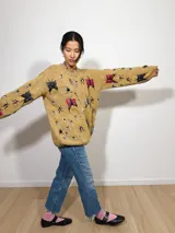 Sweater tejido color ocre con cuello redondo y bordado de bichos de diferentes colores.