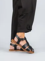 Sandalias bajas doradas con diseño de tiras entrecruzadas y hebilla lateral.