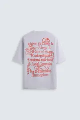 Sudadera lila de corte holgado con cuello redondo y manga corta. Presenta textos estampados en color rojo en el frente y la espalda. Tiene efecto lavado y acabados irregulares.