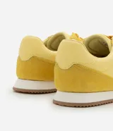 Championes amarillos con detalles en lila, de estilo vintage con punta redonda, cordones y recortes contrastantes. Suela marrón con base blanca.