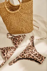 Conjunto de bikini blanco con textura, compuesto por un corpiño de triángulo fijo con breteles regulables y almohadillas desmontables, y una bombacha vedetina con frunce elástico en los costados.