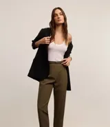 Pantalón de vestir azul marino, de corte zanahoria, con cinturón fino negro con hebilla dorada.