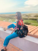 Sweater negro con detalles bordados de colores en el frente y mangas largas. Tiene cuello redondo y puños y ruedo acanalados. El cuerpo es de color rojo y las mangas son negras.