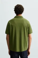 Polo de piqué color crudo, corte regular fit, cuello solapa con cierre de botonadura y mangas cortas.