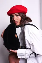 Cartera negra de PU tipo gamuza con diseño curvo y minimalista. Tiene correa regulable de nudos chunky y cierre superior.