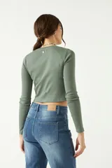 Remera blanca de manga larga con cuello redondo y corte cropped.