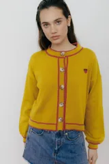 Cardigan amarillo mostaza de tejido de punto con botones, ribete rosa y bordado de cereza en el pecho.