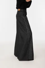 Pantalón wide leg de denim negro con tachas plateadas en el frente.