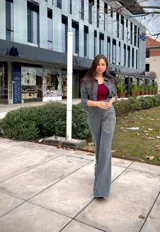 Chaqueta de jean gris con cuello clásico, cierre frontal con botones, dos bolsillos con solapa en el pecho y estampado de rosas con strass en el frente y la espalda.