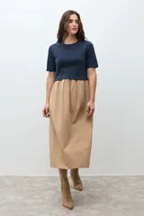 Vestido de dos piezas, con la parte superior tipo camiseta de manga corta y cuello redondo en color azul marino, y la parte inferior tipo falda midi de corte amplio y fruncido en color beige.