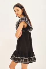 Vestido negro corto de corte amplio con bordados florales blancos en el frente, mangas y ruedo.