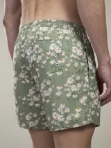 Short de baño verde con estampado de margaritas blancas y cordón ajustable naranja.