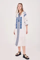 Vestido túnica blanco con bordados azules, mangas 3/4 y cuello con lazo ajustable.