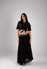 Camisa corta negra de manga corta con broderie en el frente y mangas. Se ata con un nudo en la parte delantera.