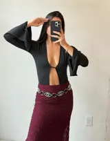 Body negro con escote en V pronunciado, mangas largas acampanadas y abertura en el abdomen.