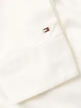 Camisa de manga larga color blanco hueso, de pana de algodón, con cuello clásico, cierre frontal con botones y logo de Tommy Hilfiger bordado en el puño.
