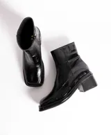 Bota corta de cuero charol negro, con caña baja, cierre lateral y taco cuadrado de madera.