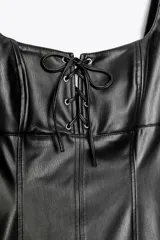 Vestido mini negro de cuero sintético, con escote recto, tirantes anchos y cierre frontal con lazada.