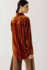 Camisa beige de terciopelo con cuello clásico, cierre frontal con botones, dos bolsillos de parche en el pecho y mangas largas con puños abotonados.